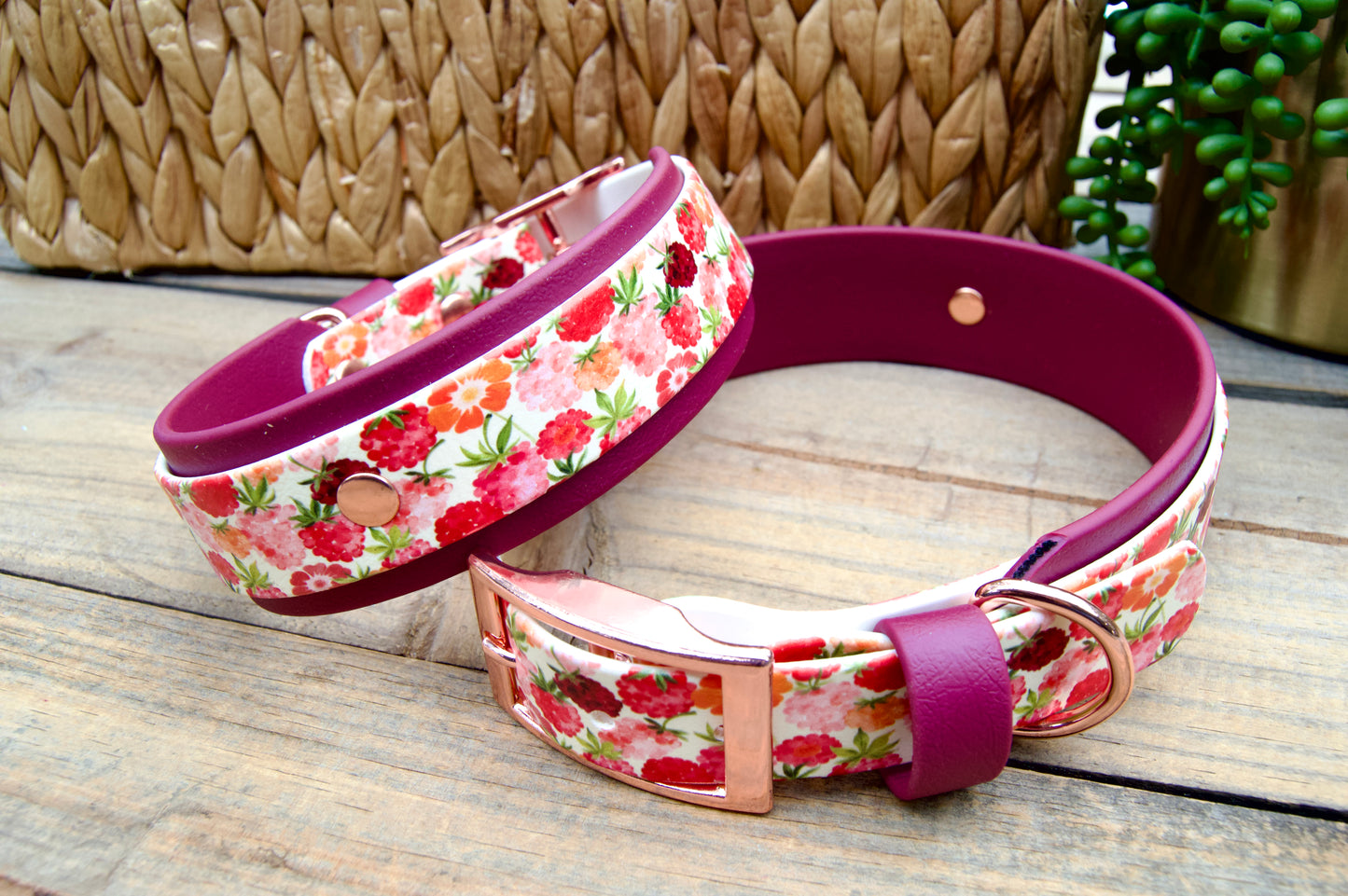 raspberry patterned dog collars with burgundy accents on a wooden surface.