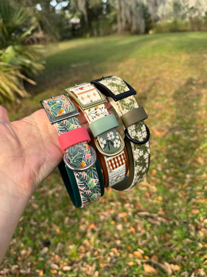 Stack of colorful patterned biothane dog collars held in a hand with a natural background