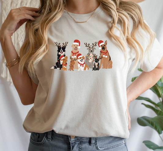 A person wearing a beige t-shirt with a graphic of dogs dressed in Santa hats and reindeer antlers.