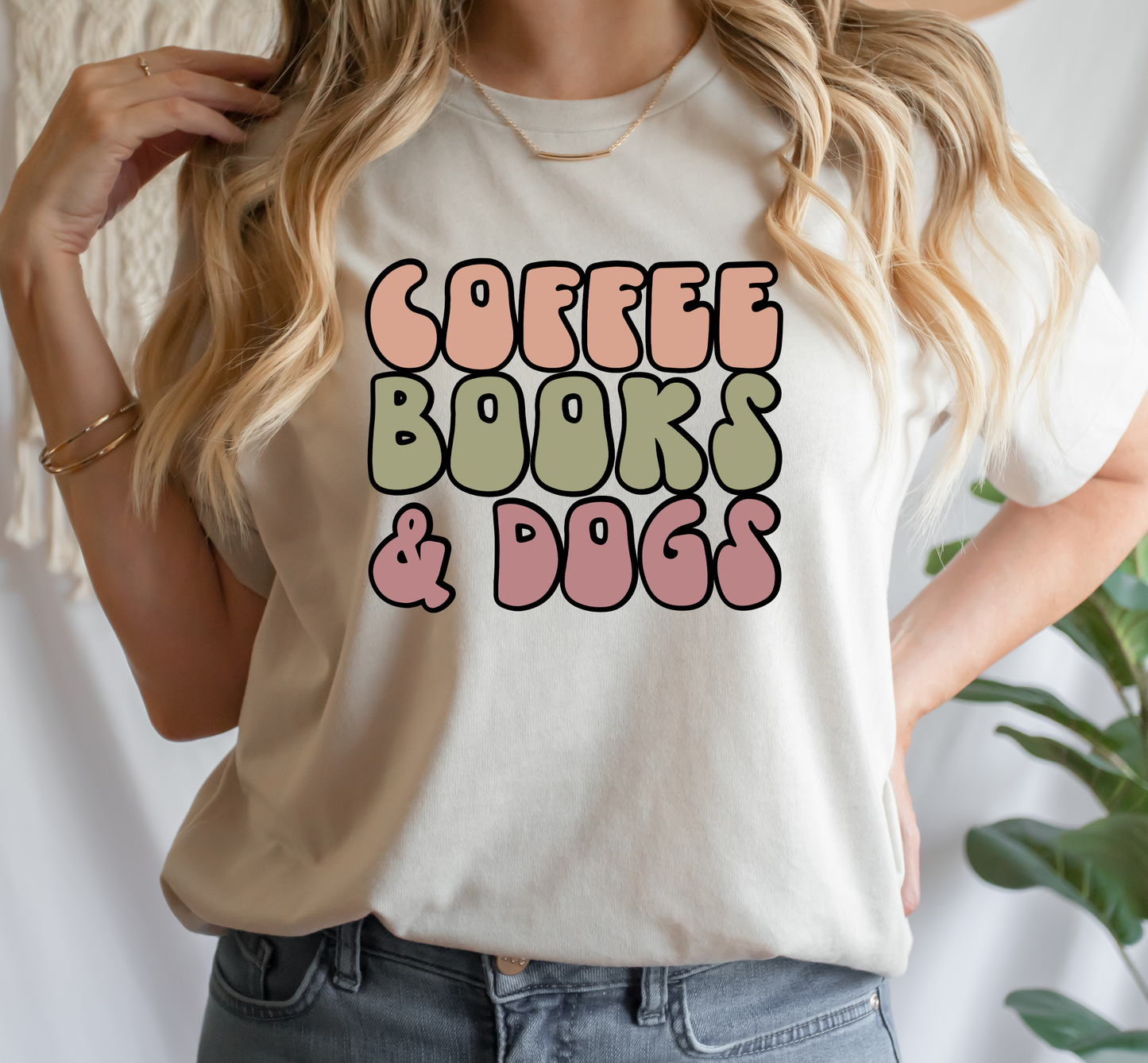 Beige T-shirt with words Coffee, Books, and Dogs in bubbly letters. 