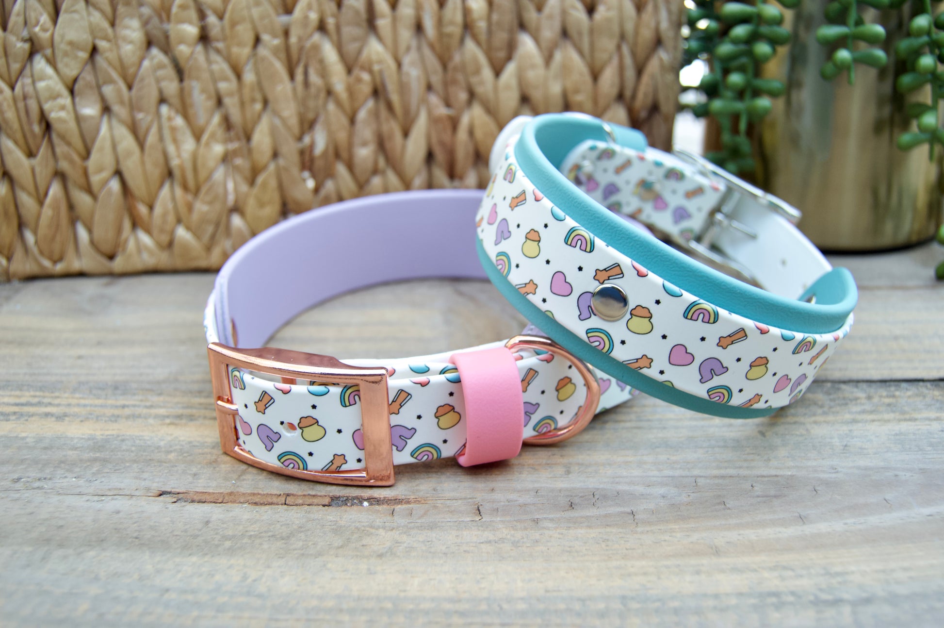 Two colorful dog collars on a wooden surface with a woven basket and plant in the background.