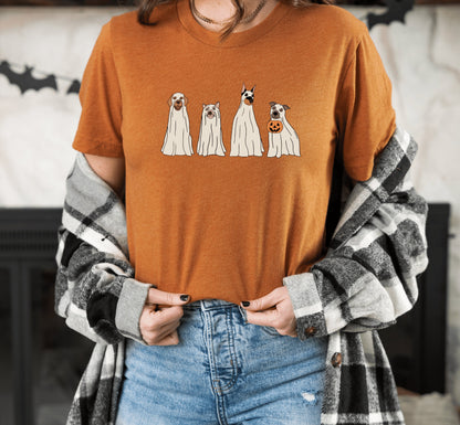 A person wearing an orange t-shirt with a graphic of four dogs dressed as ghosts in, paired with blue jeans.