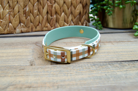 Dog collar with plaid pattern and gold buckle on a wooden surface
