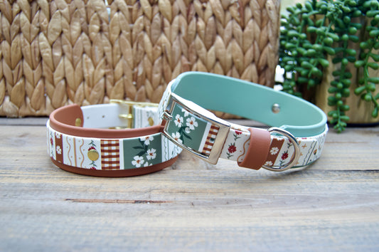 2 biothane dog collars with a striping floral design on a wooden surface with a natural basket and plant in the backgrounds