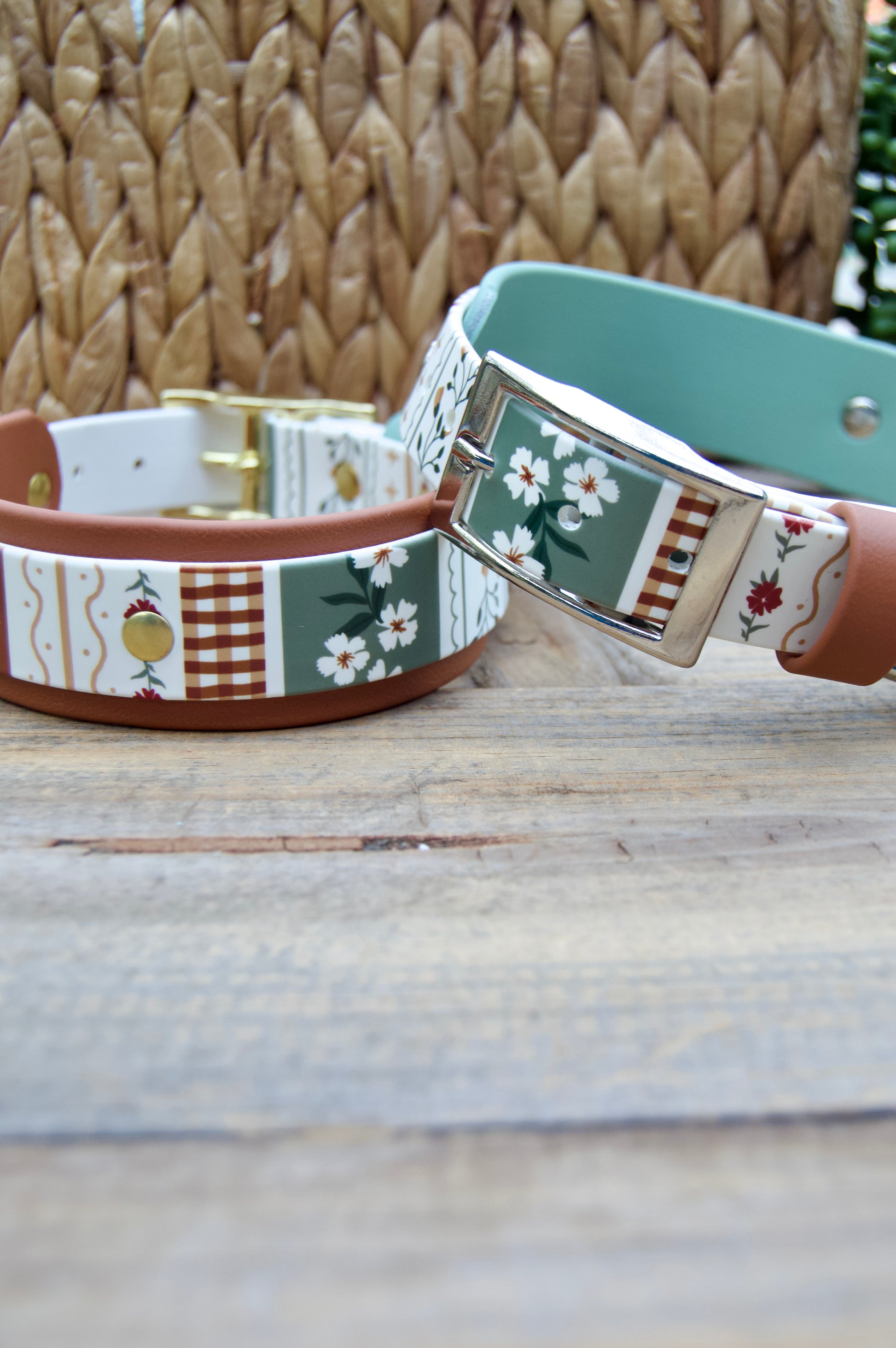 two biothane dog collars with a striping floral design and sage green accent on a wooden surface with a natural basket and plant in the backgrounds
