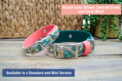 Two tropical floral-patterned dog collars in pink and green on a wooden surface with a woven basket and plants in the background.