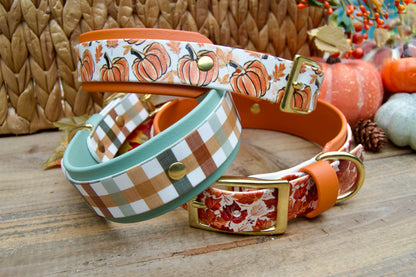 Three dog collars from the fall collection, Pumpkins, Fall Plaid and Fall Leaves, stacked on a wooden surface.