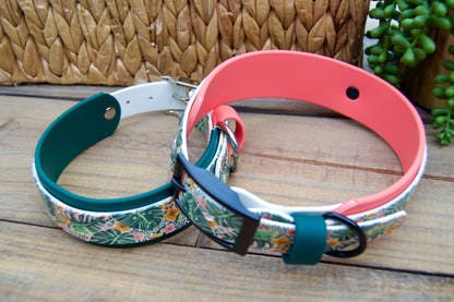 Two biothane floral-patterned dog collars on a wooden surface with a woven basket and plant in the background.